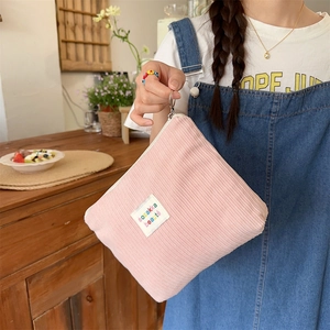 Pink corduroy makeup bag held by model showing its portable size and soft texture