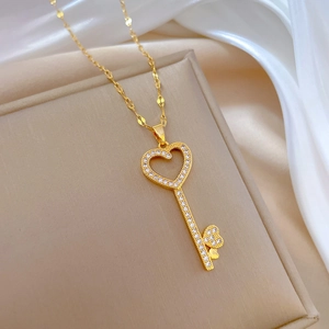 Close-up of gold heart-key pendant necklace with crystal pave on a beige jewelry box