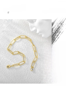 Detail einer goldenen Büroklammerkette mit funkelndem runden Kristallanhänger für Damen