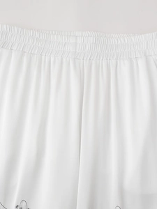 Detailed close-up of elastic waistband on white beaded embroidered trousers