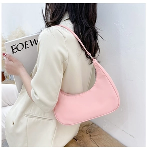 Detailed side view of a pink nylon half-moon shoulder bag styled with a beige blazer
