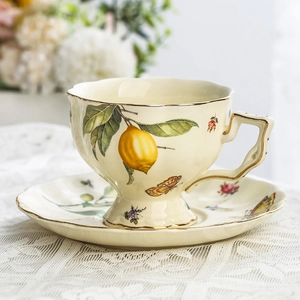 Vintage ceramic lemon pattern tea cup set with gold trim on lace tablecloth
