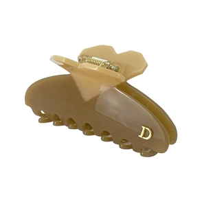 Macro view of caramel brown hair claw clip with golden D logo and heart design detail