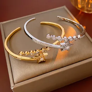 Gold and silver star open bangles with sparkling cubic zirconia on brown jewelry box