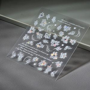 3D nail art stickers with white flowers, pearls, and iridescent butterflies on gray background