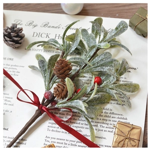 Close-up of frosted Christmas mistletoe branch with pinecones, red berries, and ribbon