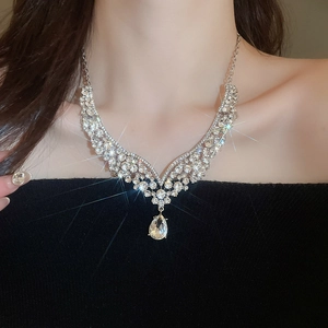 Close-up of sparkling V-shaped silver necklace with pear-cut crystal pendant on model