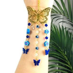 Close-up of golden hollow butterfly car charm with evil eye and blue floral beads decor