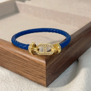 Dettaglio del bracciale in pelle intrecciata blu con fibbia a catena ad ancora dorata