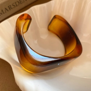 Macro view of amber resin cuff bracelet with tortoiseshell texture on shell tray