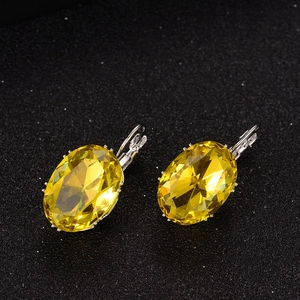 Macro shot of silver lever-back earrings with large oval-cut yellow crystal gemstones