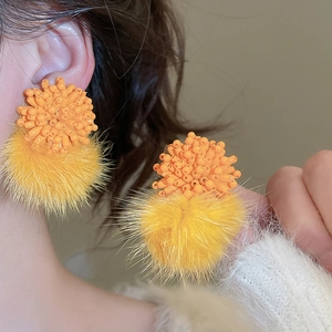 Detailed close-up of beaded flower earrings with orange beads and yellow fur pom poms