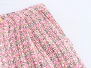 Gros plan sur le tissu en tweed rose avec un bouton doré décoratif à la taille