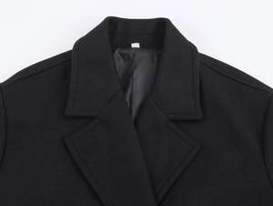 Detail of classic notched lapel collar on black wool blend coat with neat stitching