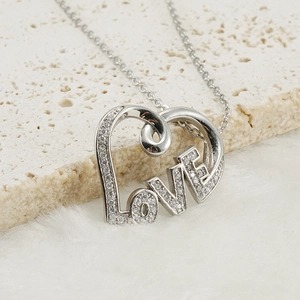 Macro shot of silver heart pendant with LOVE letters and diamonds on a stone base
