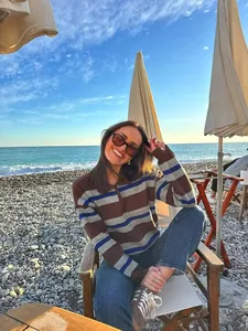 Detail of a casual long-sleeve polo knit sweater with colorful stripes on a beach