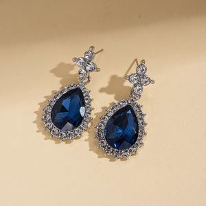 Dettaglio macro di orecchini vintage con cristallo blu a goccia e decori argentati