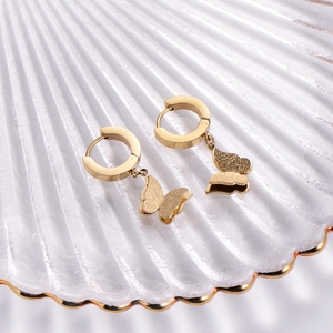 Elegant gold butterfly hoop earrings with a matte textured finish on shell tray