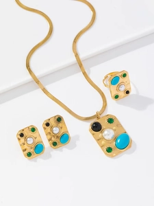 Détails de parure dorée ornée de pierres turquoises, vertes et de perles blanches