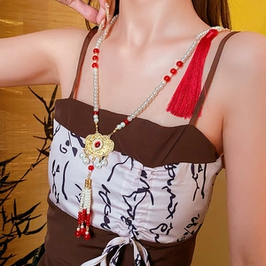 Detailed close-up of a Phoenix glass lock necklace with red silk tassel and pearls