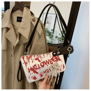 Macro shot of cleaver-shaped Halloween handbag with blood splatter and bone pendant