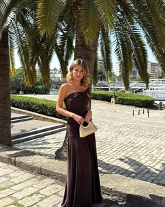 Detail of dark brown one-shoulder dress with side ruching and elegant gold handbag