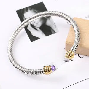 Detail of twisted cable cuff bracelet with gold end caps and purple gemstones