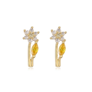 Detail of floral earrings with gold metal, white zircons and yellow leaf-shaped gemstone