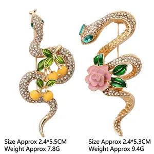 Snake brooch set with gold base, clear crystals, floral details, and green gem eyes
