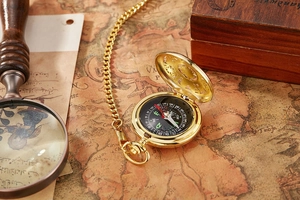 Close-up of golden pocket watch compass on vintage map for outdoor hiking adventure