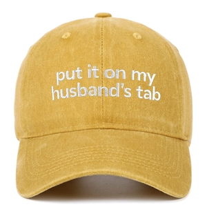 Detail of white embroidery on yellow washed cotton baseball cap with vintage texture