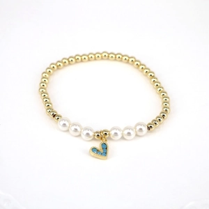 Close-up of pearl and gold bead bracelet featuring a blue heart-shaped pendant