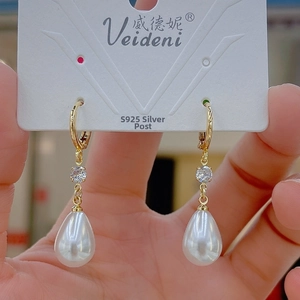 Detailed macro shot of S925 silver needle pearl earrings with gold drop accents