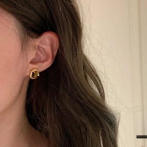Detailed view of 18k gold plated tiger eye oval stud earrings worn by a model