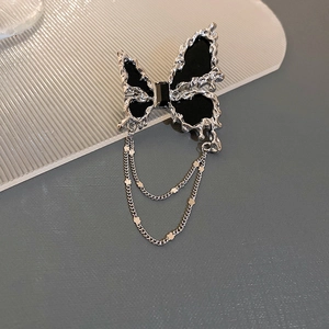 Broche papillon argentée aux ailes noires, chaînes d'étoiles et design en métal liquide