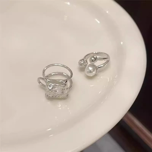 Detailed view of silver rings featuring a large pearl and textured square design