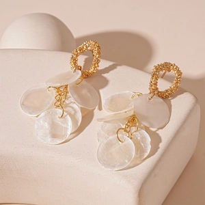 Detail of gold textured hoop earrings with white translucent discs on stone