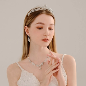 Close-up of bridal jewelry set with silver crystal crown, necklace, and earrings