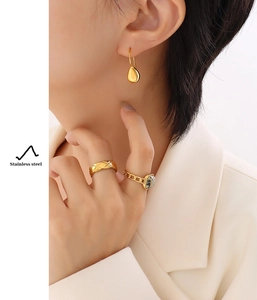 Detail of 18k gold plated stainless steel teardrop earrings and rings on model