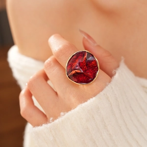 Close-up of a red enamel ring with gold metal finish worn on a model's finger