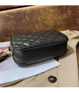 Detail of black quilted camera bag with elegant tassel and gold-tone hardware accents