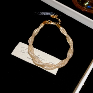 Detailed view of a gold twisted mesh bracelet in a premium black and white gift box