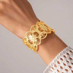 Detailed view of 18k gold plated cutout floral cuff bracelet with sparkling zircons