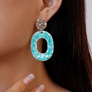 Detail shot of hammered silver metal stud and marbled blue enamel oval hoop earrings