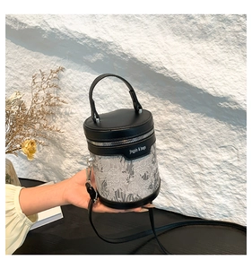 Detail of black PU leather bucket bag with semi-transparent floral mesh and crossbody strap