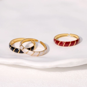 Detail of adjustable gold-plated enamel rings in black, white, and red with gold stripes