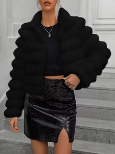 Detail of short black faux fur jacket with zipper paired with crocodile skirt