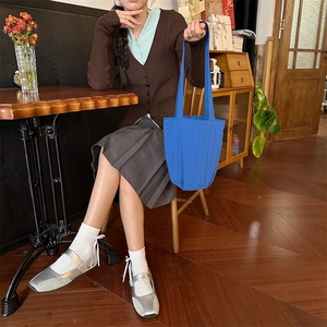 Blauwe gestreepte bucket bag gedragen door een model in een gezellige koffiebar