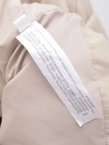 Close-up of the 100% cotton fabric washing label on a beige casual jacket