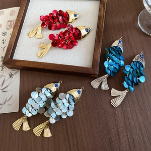 Macro detail of a fish-shaped shell hair clip featuring metallic accents and layered scales